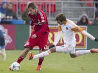 Justin Braun, izquierda, del Toronto FC, dispara bajo la marca de Eric Brunner, del Dynamo de Houston, durante el segundo medio del encuentro del sábado 20 de abril de 2013, en Toronto.  Foto: The Canadian Press, Chris Young / AP