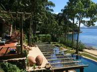 Casa em Ubatuba tem piscina a poucos passos do mar. Foto: Bertrand Cocallemen/ Renata Pati Arquitetura