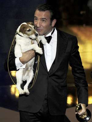 ARCHIVO - En esta imagen del 26 de febrero de 2012, el actor Jean Dujardin sostiene a Uggie tras recibir el Oscar a la mejor película por “The Artist” durante la 84ta edición de los Premios de la Academia en Hollywood. Uggie, el terrier de Jack Russell que participó en cintas como "The Artist," "The Descendants" y "Water for Elephants", contará con su propio libro biográfico, se anunció el viernes 27 de abril de 2012.  Foto: Mark J. Terrill, archivo / AP