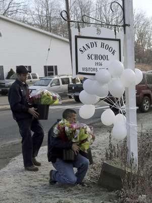 Bomberos voluntarios colocan flores en un monumento improvisado en la entrada de la escuela primaria Sandy Hook el sábado 15 de diciembre de 2012 en Newtown, Connecticut. La familia de una niña boricua de 6 años que murió asesinada en la matanza en la escuela se había mudado a Estados Unidos apenas dos meses antes de la tragedia.  Foto: Mary Altaffer / AP