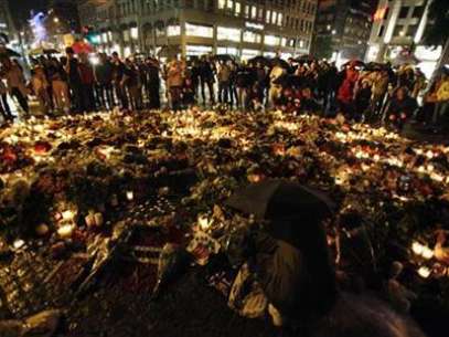 Un grupo de personas se protegen de la lluvia con sus paraguas mientras recuerdan con velas y flores a las víctimas de la masacre ocurrida en Noruega. Foto: Wolfgang Rattay / REUTERS