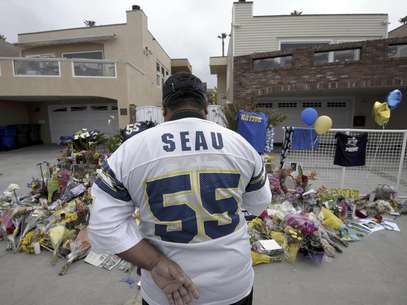 El seguidor de los Chargers de San Diego, Jerry López, observa las ofrendas colocadas frente a la casa del ex jugador de la NFL, Junior Seau, el jueves, 3 de mayo de 2012, en Oceanside, California. Seau fue hallado muerto en su residencia el miércoles, 2 de mayo.   Foto: Denis Poroy / AP