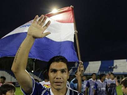 El delantero Salvador Cabañas saluda frente a una bandera paraguaya durante un encuentro entre 12 de octubre y Martín Ledesma por la tercera división del fútbol paraguayo en Itauguá, abr 14 2012. El entrenador del club paraguayo en el que juega Salvador Cabañas -quien volvió al fútbol luego de recibir un disparo en la cabeza- renunció el miércoles, por lo que consideró presiones para incluir entre los titulares del equipo al delantero. Foto: Jorge Adorno / Reuters
