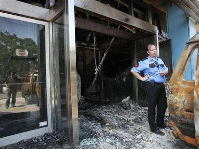 A security guard stands near a damaged van outside the burnt entrance of Microsoft's Greek headquarters following an attack at Marousi suburb, north of Athens June 27, 2012. Foto: John Kolesidis / Reuters In English