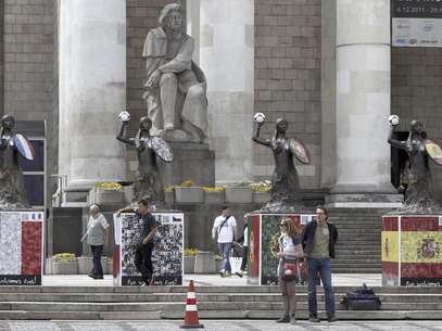 La gente camina entre sirenas, el símbolo de la ciudad de Varsovia, decoradas con las banderas de los países que fueron representados en la Euro 2012 en Varsovia, Polonia, el viernes 13 de julio de 2012. La UEFA obtendría ganancias ligeramente menores por la Euro 2012, en comparación con el campeonato de hace cuatro años.  Foto: Czarek Sokolowski / AP