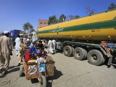 Men push a family past a fuel tanker, carrying supplies for NATO Forces, at the Pakistan-Afghan border of Torkham October 10, 2010. Foto: K. Parvez / Reuters In English