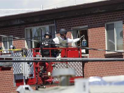 Law enforcement officers put a container filled with blue liquid to use in an explosion at the apartment where suspect James Eagan Holmes lived in Aurora, Colorado July 21, 2012. Foto: Joshua Lott / Reuters In English