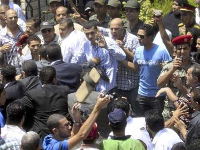 Relatives of slain Egyptian border guards throw shoes at Egypt's Prime Minister Hisham Kandil (in suit, back to camera, 2nd L) during the military funeral for the guards at the Omar Makram mosque in Cairo August 7, 2012. Foto: Mohamed Abd El Ghany / Reuters In English