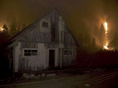 A wooden structure sits on the side of the road near Pine and Featherville, Idaho as flames from the Trinity Ridge Fire in the Boise National Forest engulf trees in this August 17, 2012 handout photograph made available to Reuters August 19, 2012. Foto: Handout / Reuters In English