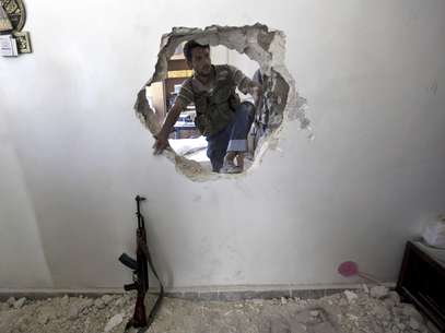Un rebelde sirio entra por el orificio de una pared en busca de sobrevivientes tras un bombardeo militar en Alepo, Siria. Foto: Khalil Hamra, Archivo / AP