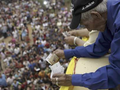 José Antonio Medina arroja billetes que equivalen a 50 centavos de dólar a niños pobres desde el balcón de una iglesia en Guarambare, Paraguay, en agradecimiento por su buena fortuna. Foto: Jorge Saenz / AP