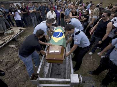 Varios policías colocan en la tumba el féretro con los restos de su compañero caído Diego Bruno Barbosa Henriques, en un cementerio en Río de Janeiro, Brasil, el viernes 14 de septiembre de 2012. Una bandera brasileña cubre el ataúd. Barbosa fue asesinado con arma de fuego el jueves en la noche mientras efectuaba un patrullaje a pie en el barrio pobre de Rocinha, en la ciudad. Barbosa es el tercer agente asesinado en los barrios pobres en los que las autoridades han reinstalado el orden en Río.  Foto: Víctor R. Caivano / AP