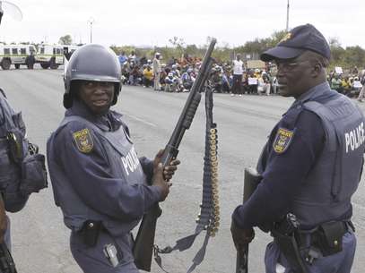 Mineros en huelga, fondo, desfilan en Rustenburg, Sudáfrica, frente a un cuartel policial el domingo, 15 de septiembre del 2012, en protesta por la represión policial. La marcha fue declarada ilegal por la fuerza pública.  Foto: Denis Farrell / AP