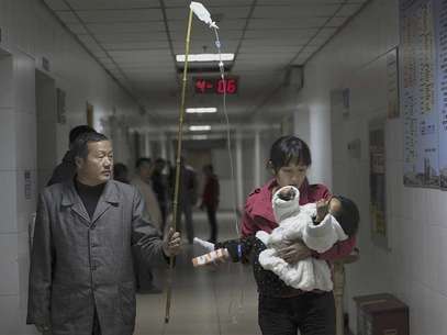 A man uses a stick to hold up a drip for his granddaughter, who is held by her mother, as the girl receives an intravenous injection at a hospital in Hefei, Anhui province, in this November 30, 2011 file picture. Foto: Files / Reuters In English
