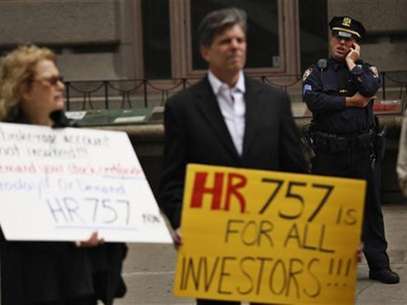 A police officer keeps an eye on demonstrators while they hold a protest warning investors that they too could become victims of a Wall Street fraud in New York May 8, 2012. Victims of the Bernard Madoff investment fraud took part and helped organize the demonstration. Foto: Eduardo Munoz / Reuters In English