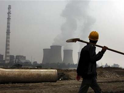 A coal-burning power station can be seen behind a migrant worker as he walks carrying his shovel on the construction site of a water canal, being built in a dried-up river bed located on the outskirts of Beijing October 22, 2010. Foto: David Gray / Reuters In English