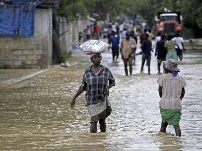 Unas personas caminan por calles inundadas por el huracán Sandy, en La Plaine, Haití, el jueves 25 de octubre de 2012. El huracán dejó al menos 69 muertos en su paso por el Caribe y se dirige a costa este de EEUU.  Foto: The Miami Herald, Carl Juste / AP