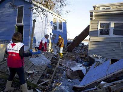 Red Cross volunteers Jessica Elam and Gilbert Abney check on Rob Fragetti, who is attempting to salvage items with his neighbors in their destroyed homes, in this handout photo from the American Red Cross, in Staten Island, New York, in this November 6, 2012 file photo. Foto: Talia Frenkel / Reuters