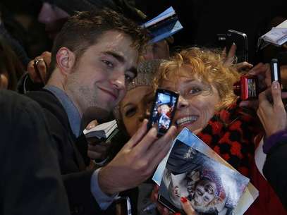Actor Robert Pattinson poses for a photo with a fan as he arrives for the European premiere of "The Twilight Saga: Breaking Dawn Part 2" in London November 14, 2012. Foto: Luke MacGregor / Reuters