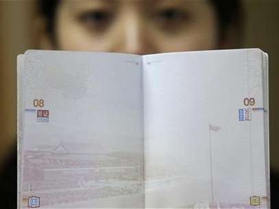 A woman holds a Chinese passport, displaying a Chinese map which includes an area in the South China Sea inside a line of dashes representing maritime territory claimed by China (L, top) and a picture of Beijing's Tiananmen Square (bottom), at an office in Wuhan airport, Hubei province, November 23, 2012. The Philippines and Vietnam condemned Chinese passports containing a map of China's disputed maritime claims on Thursday, branding the new design a violation of their sovereignty. Foto: Stringer / Reuters