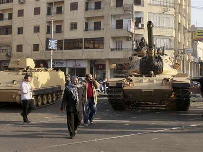 Supporters of the Muslim Brotherhood walk past tanks that were just deployed outside the Egyptian presidential palace in Cairo December 6, 2012. At least three tanks are deployed outside the palace on Thursday in a street where supporters and opponents of President Mohamed Mursi had been clashing into the early hours of the morning, a Reuters witness said. Foto: Asmaa Waguih / Reuters