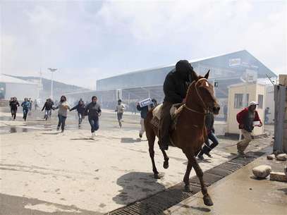A policeman fires tear gas at people who tried to loot a supermarket as they throw stones at police in San Fernando, on the outskirts of Buenos Aires, December 21, 2012. At least two people were killed in Argentina as looters broke into supermarkets in several cities, stirring memories of the country's devastating economic crisis 11 years ago. The violence erupted on Thursday in the Patagonian ski resort of Bariloche when dozens of looters stormed a supermarket and made off with LCD televisions and other goods. Government officials condemned the violence and deployed 400 military police to the southern city. Similar unrest broke out in the central city of Rosario and in several parts of the urban sprawl that surrounds the capital Buenos Aires early on Friday. Foto: Enrique Marcarian / Reuters