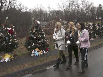 En imagen del lunes 17 de diciembre de 2012, tres mujeres llevan esferas para decorar los árboles de Navidad en uno de los monumentos improvisados para las víctimas de la matanza en la escuela primaria Sandy Hook, en Newtown, Connecticut. Tras el tiroteo, la ciudad trata de reencontrar el significado de la Navidad.  Foto: Mary Altaffer, archivo / AP
