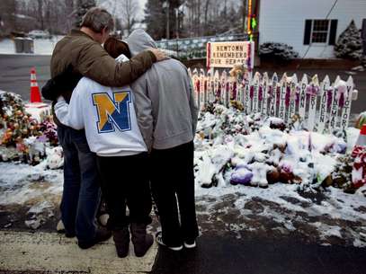 Miembros de la familia Rutter, de Sandy Hook, Connecticut, se abrazan en la mañana del martes 25 de diciembre de 2012, el día en que se celebra la navidad en Estados Unidos, cerca de improvisados monumentos en el estación de bomberos de Sandy Hook, en Newtown, Connecticut. Los habitantes siguen visitando los monumentos después de que Adam Lanza se abrió paso a disparos el 14 de diciembre en la escuela Sandy Hook en Newtown, Connecticut, y mató a 26 personas, incluyendo 20 niños, antes de suicidarse.   Foto: Craig Ruttle / AP