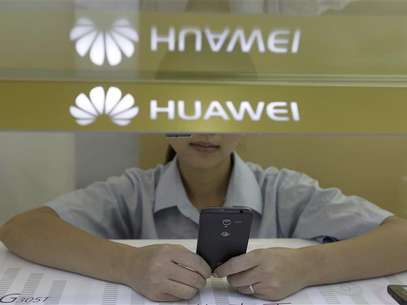 A sales assistant looks at her mobile phone as she waits for customers behind a counter at a Huawei booth in Wuhan, Hubei province, in this October 10, 2012 file photo. A major Iranian partner of Huawei Technologies offered to sell at least 1.3 million euros worth of embargoed Hewlett-Packard computer equipment to Iran's largest mobile-phone operator in late 2010, documents show. Foto: Stringer / Reuters