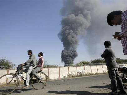 Onlookers stand as smoke billows from Indian Oil Corporation's fuel depot in Hazira, near Surat city of India's western state of Gujarat January 5, 2013. A major fire broke out at an IOC fuel depot on Saturday in Hazira with no reports of casualties or injuries, according to local media. Foto: Amit Dave / Reuters