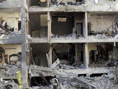 Free Syrian Army fighters and residents are seen near buildings damaged after what activists say were missiles fired by Syrian Air Force fighter jets loyal to Syria's President Bashar al-Assad, in Erbeen, near Damascus January 21, 2013, in this picture provided by Shaam News Network. Foto: Maawia Al-Naser / Reuters