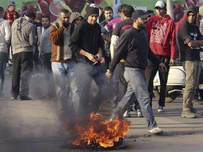 Ultras soccer fans gather around tyres they burnt over a bridge during a rally to demand justice for 74 people killed in a stadium stampede last year, in central Cairo January 23, 2013. Foto: Stringer / Reuters