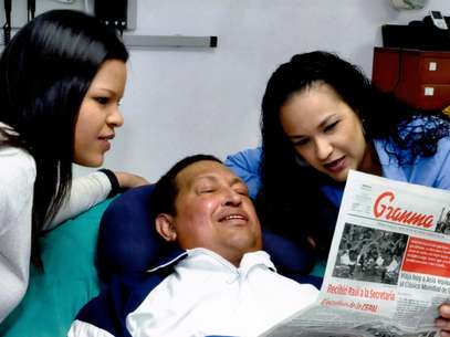 En esta foto distribuida por la oficina de prensa del gobierno venezolano el viernes 15 de febrero de 2013, aparece el presidente Hugo Chávez, junto a sus hijas Maria Gabriela, izquierda, y Rosa Virginia mientras leen el diario cubano Ganma en Cuba del jueves 14 de febrero de 2013. Foto: Miraflores Presidential Press Office / AP