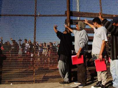A group of recently deported immigrants stand near the double steel fence that separates San Diego and Tijuana at the border in Tijuana December 10, 2011. Foto: Jorge Duenes / Reuters