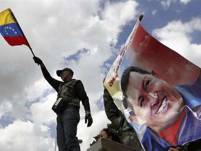 A supporter of Venezuela's President Hugo Chavez waves a national flag next to a giant picture of Chavez, in front of a military hospital where Chavez is being treated, in Caracas February 19, 2013. Foto: Carlos Garcia Rawlins / Reuters