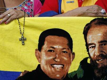 A supporter of Venezuela's President Hugo Chavez holds a crucifix next to a picture of Chavez with Cuba's former leader Fidel Castro (R) in Caracas January 5, 2013. Foto: Carlos Garcia Rawlins / Reuters