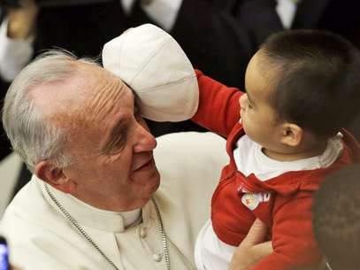 Criança brinca com o chapéu do Papa durante a audiência de sábado no Vaticano Foto: AP
