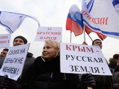Mulher segura uma placa com a frase "Crimeia é terra russa!" e "Não mudamos nossas pessoas por dinheiro!" durante protesto no centro de Moscou, nesta sexta-feira, 7 de março Foto: AFP