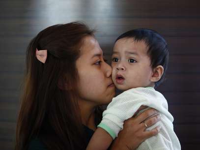 Erny Khairul, mulher do engenheiro de voo Mohd Selamat, a bordo no avião desaparecido beija sua filha em hotel, onde esperam notícias sobre avião em Putrajaya Foto: Reuters