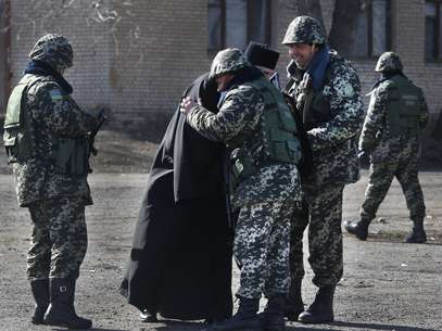 Soldados recebem um religioso na base militar de Alekseyevka, na fronteira entre a Ucrânia e a Crimeia Foto: AP