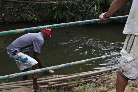 Moradores se arriscam para pegar Ã¡gua de bica no Canal das Taxas, onde vivem jacarÃ©s Foto: Ariel SubirÃ¡ / Futura Press