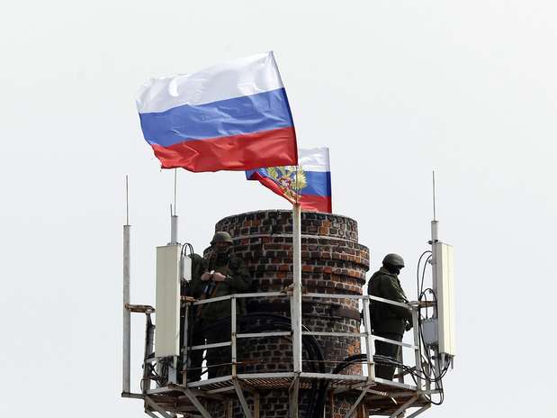 Homens armados hasteiam a bandeira russa no topo de uma chaminé da base nava de Sebastopol - tomada pelos russos sem disparos na manhã desta quarta-feira Foto: Reuters