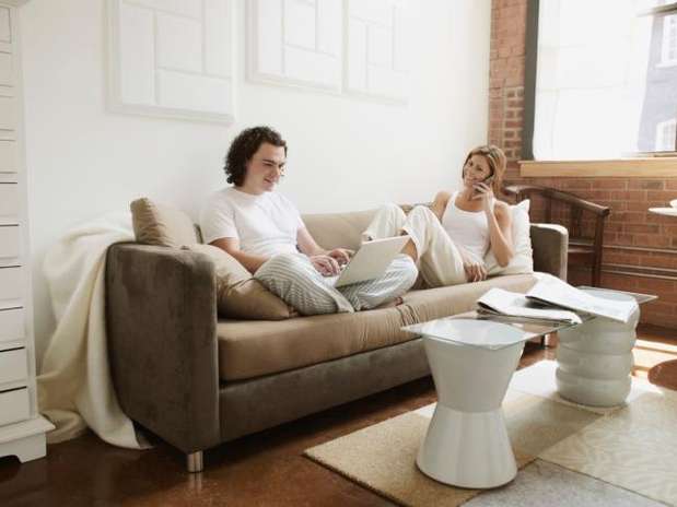 Young adult couple using laptop computer and cell phone Foto: Thinkstock