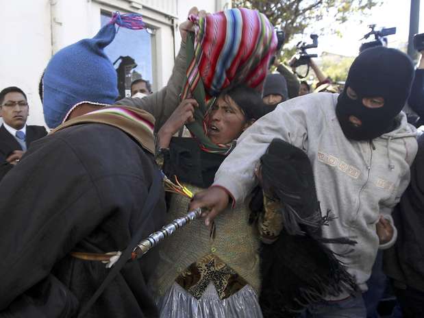 Un manifestante enmascarado golpea a un indígena Aymara que intenta ingresar a la plaza frente al palacio presidencial donde están reunidos policías de bajo rango que reclaman mejoras salariales, en La Paz, Bolivia, el lunes 25 de junio de 2012.  Foto: Juan Karita / AP
