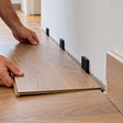 Colocar piso laminado encostado na parede: por que alguns milímetros de folga evitam que as réguas levantem quando o material se expande