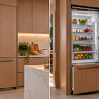 A cozinha sem geladeira aparente usa painéis e eletrodomésticos embutidos para fazer portas e armários parecerem uma única superfície