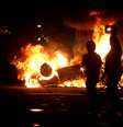 Jovens são vistos em frente ao carro queimado na noite de segunda-feira  Foto: Mauro Pimentel / Terra