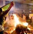 Manifestante abre a bandeira do Brasil em frente a fogueira durante confronto com a polícia, em Niterói  Foto: AFP