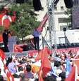 Premiê turco, ao fundo, fala em evento com simpatizantes neste sábado  Foto: Reuters