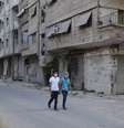 Homens usam máscara para se proteger de possíveis gases químicos ao se aventurarem por rua da área de Ain Tarma  Foto: Reuters